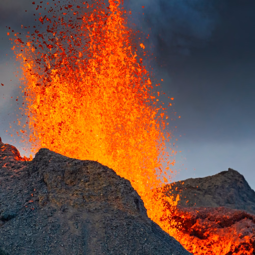 Erupcja wulkanu z wyrzucającą się lawą i dymem na tle nieba