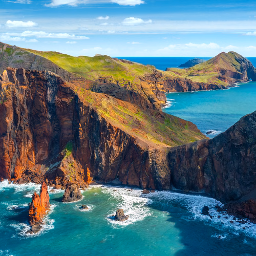 Malownicze klify nad turkusowym oceanem z zielonymi wzgórzami w tle na słoneczny dzień