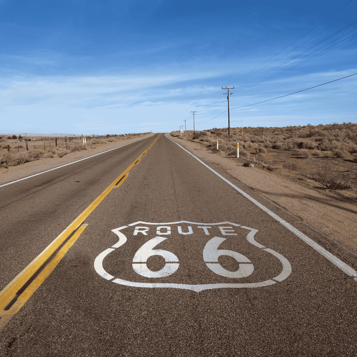 Pusta droga Route 66 wśród pustynnego krajobrazu pod błękitnym niebem